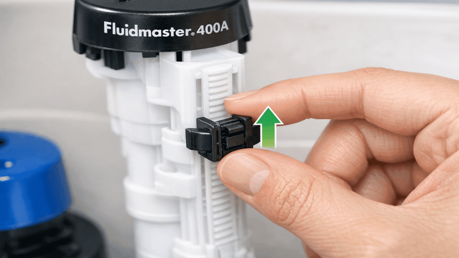 Close-up of Fluidmaster 400A float adjustment clip being pinched and slid upward along the valve body to raise the toilet tank water level