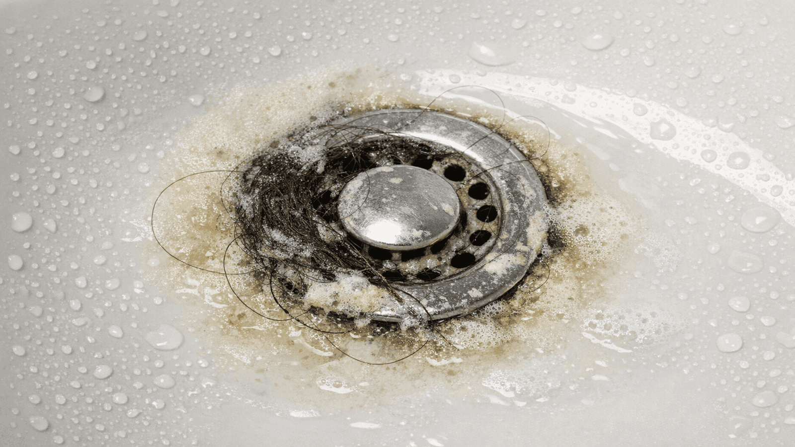 Close-up of clogged bathroom sink drain showing hair and soap buildup requiring professional cleaning
