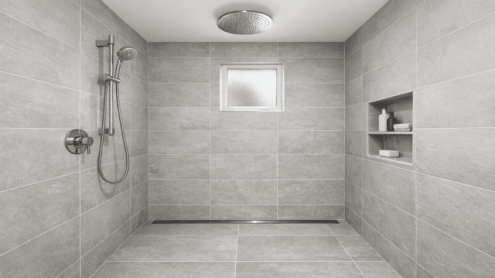 Finished modern walk-in shower with large-format gray porcelain tile, linear drain, ceiling rain head, built-in niche, and chrome fixtures