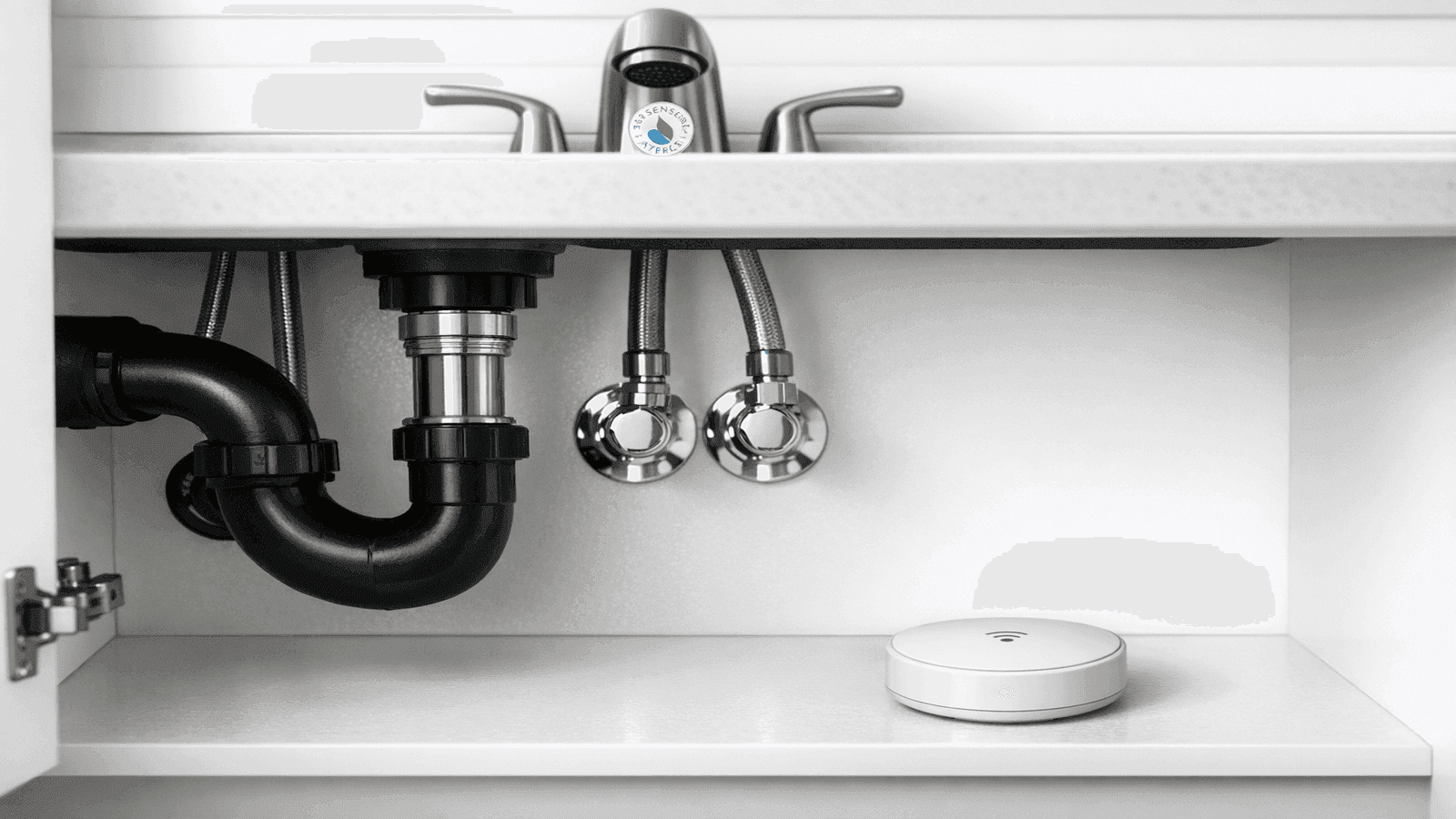 Smart leak detector sensor installed under bathroom sink next to supply lines showing water monitoring technology for eco-friendly homes